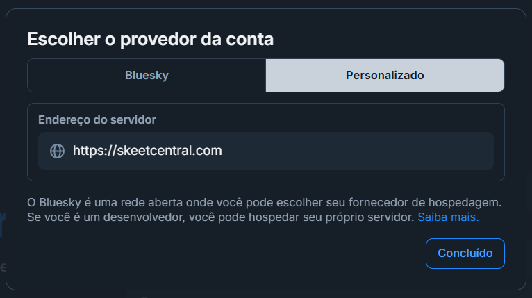 Pop-up para Escolher o provedor da conta, com duas abas: Bluesky e Personalizado.
A aba Personalizado está selecionada, exibindo o campo de Endereço do servidor preenchido com https://skeetcentral.com
Botão Concluído.